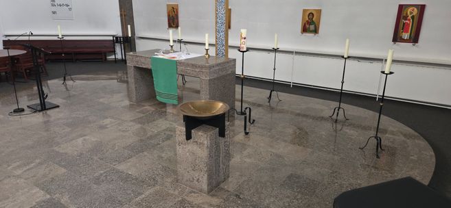 Innenansicht einer Kirche mit Altar, Kerzenständern und Ikonen an der Wand.