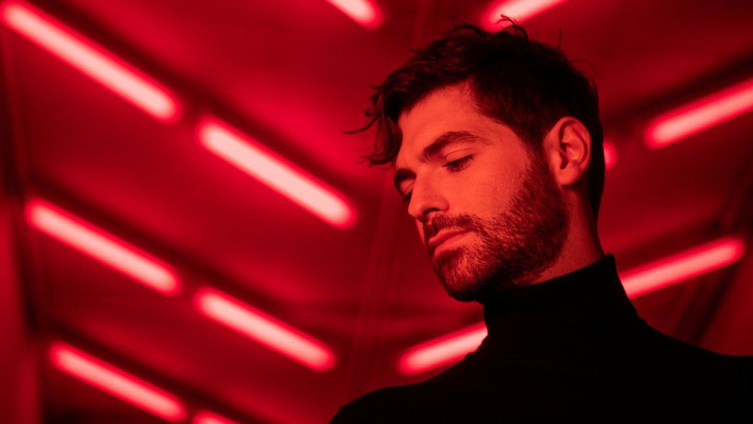 Person in rotem Licht mit nach unten gerichtetem Blick.