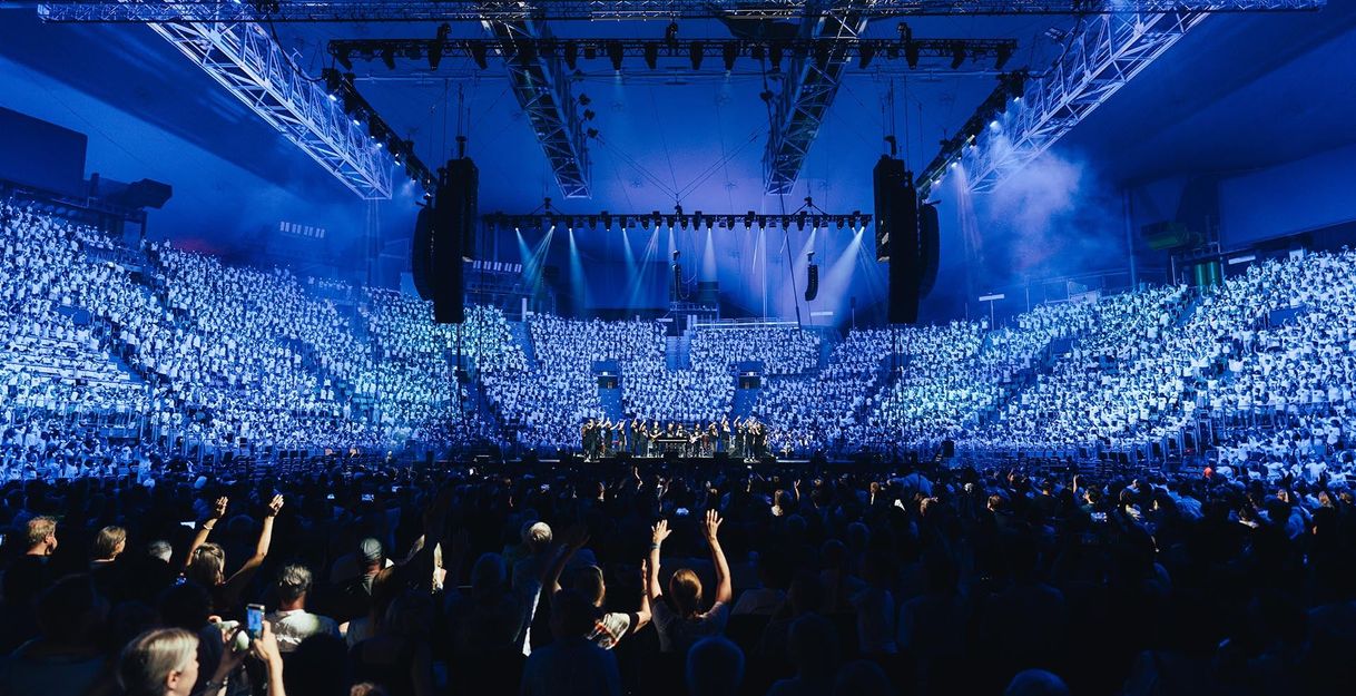 Großes Konzert mit Chor und Publikum in einer beleuchteten Arena.