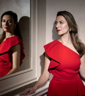 Frau in rotem Kleid vor einem Spiegel.