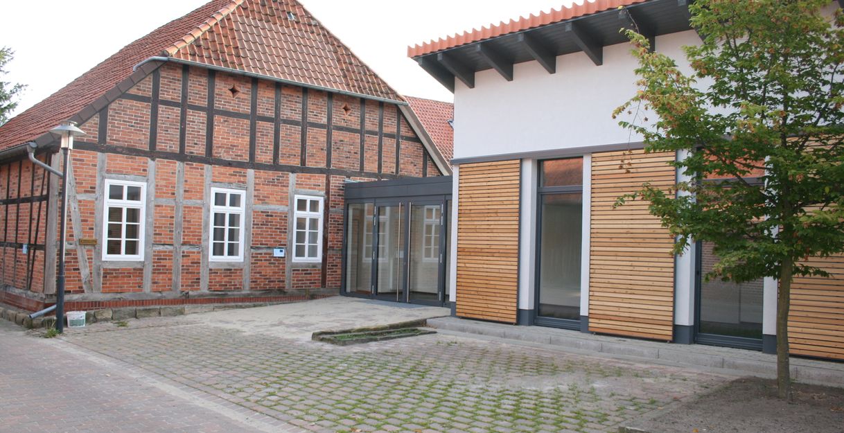 Ein Fachwerkhaus neben einem modernen Gebäude mit Holzverkleidung.