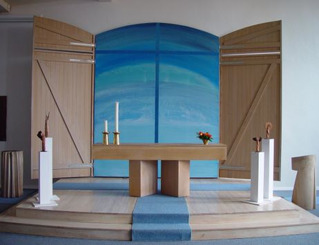 Moderner Kirchenaltar mit blauem Hintergrund und Holzverkleidung.