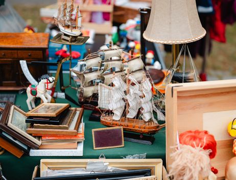 Flohmarktstand mit Modellschiffen, Bilderrahmen und einer Lampe.