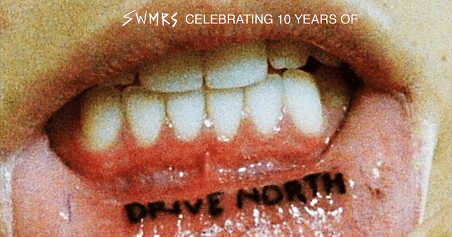 Nahaufnahme eines Mundes mit einem Tattoo auf der Innenseite der Unterlippe, das "DRIVE NORTH" sagt. Oben steht "SWMRS CELEBRATING 10 YEARS OF".