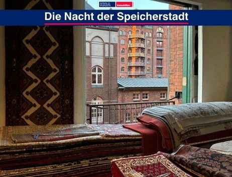 Blick aus einem Fenster auf die Speicherstadt in Hamburg, mit Teppichen im Vordergrund.