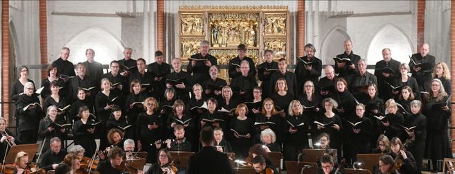 Ein Chor singt vor einem kunstvollen Altar in einer Kirche.