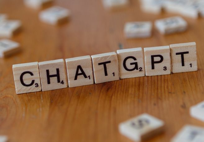 Holzbuchstaben auf einem Tisch bilden das Wort 'CHATGPT'.