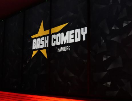 Ein Banner mit der Aufschrift 'Bash Comedy Hamburg' und einem gelben Stern auf schwarzem Hintergrund.