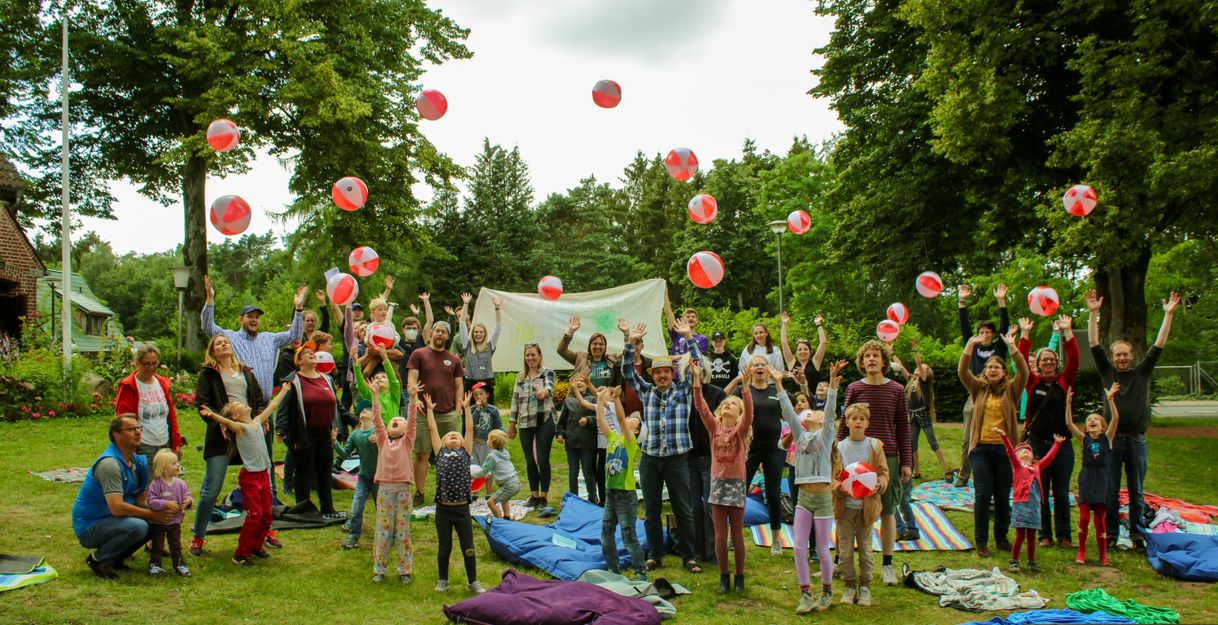 Eine Gruppe von Menschen wirft bunte Strandbälle in die Luft in einem Park.
