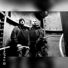 Zwei Personen in einem industriellen, metallischen Raum, schwarz-weiß Foto.