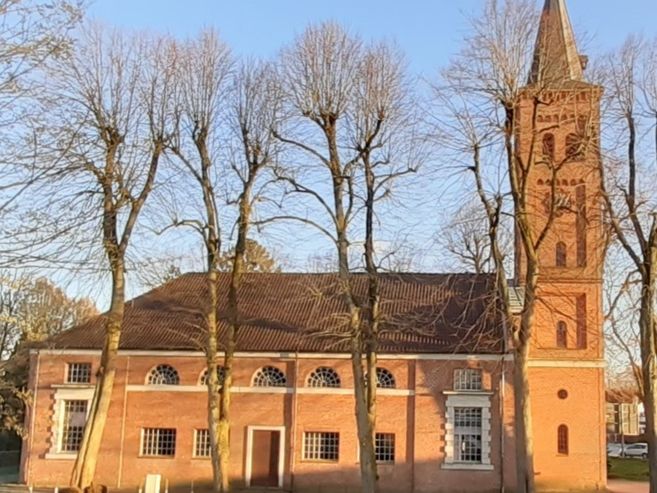 Seitenansicht der Marienkirche in Quickborn mit Bäumen im Vordergrund.