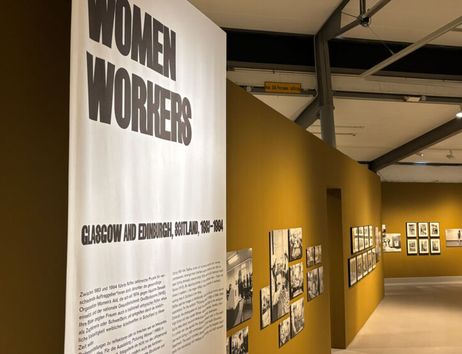 Ausstellung über Frauenarbeit in Glasgow und Edinburgh, 1850-1984, mit Fotos an gelben Wänden.