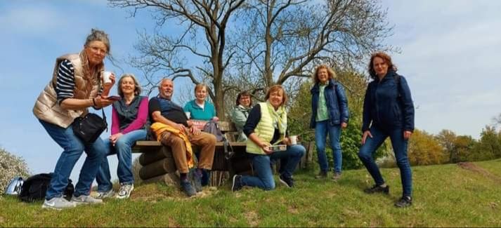 Eine Gruppe von Menschen posiert auf einer Wiese vor einem Baum.