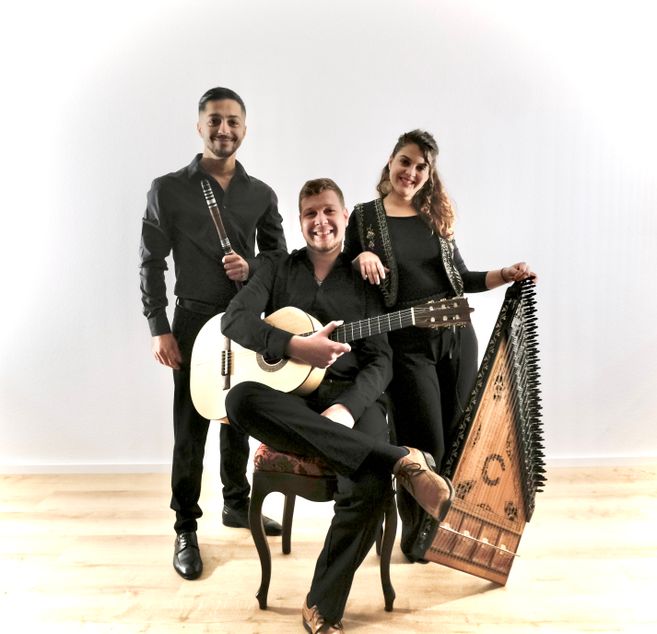 Drei Musiker des Balkan Fuego Trios posieren mit ihren Instrumenten: Gitarre, Flöte und Kanun.