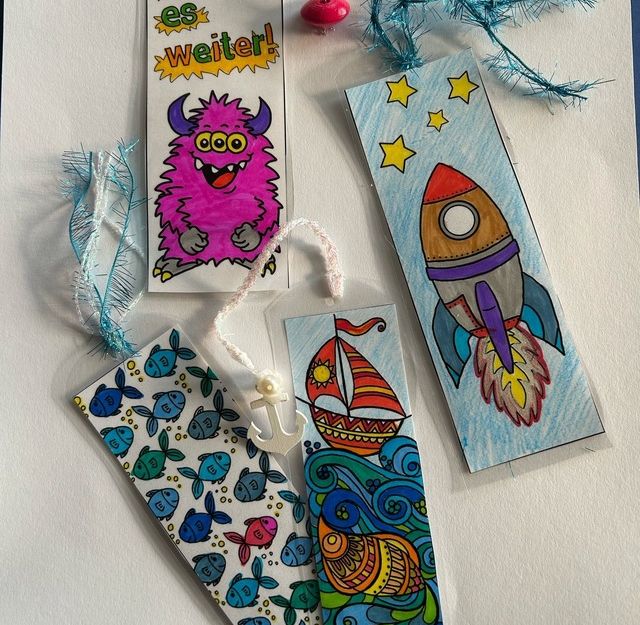 Verschiedene bunte Lesezeichen mit Motiven wie einem Monster, einer Rakete, Fischen und einem Segelboot.