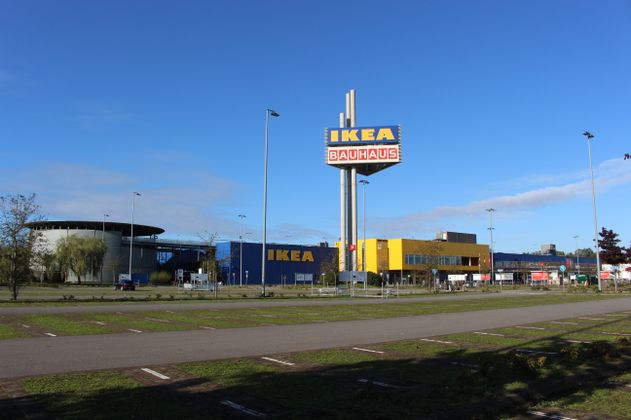 Außenansicht des IKEA Einrichtungshauses in Hamburg-Moorfleet bei Tageslicht, mit großem Parkplatz im Vordergrund und einem hohen Werbeturm, der die Logos von IKEA und BAUHAUS zeigt. Der Himmel ist klar und blau.