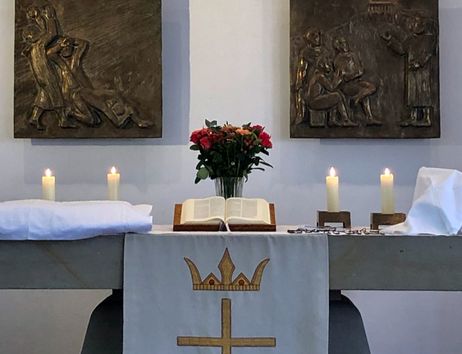 Altar in der Pauluskirche mit Bibel, Blumen und Kerzen.