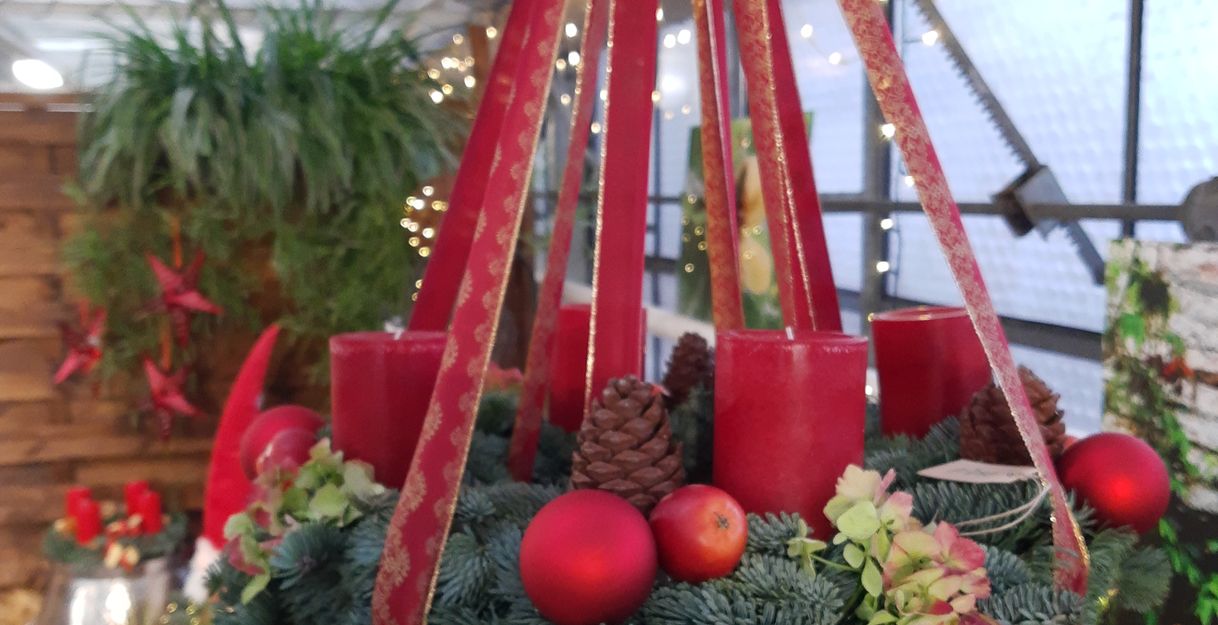 ein Adventskranz mit roten Bändern und Kerzen