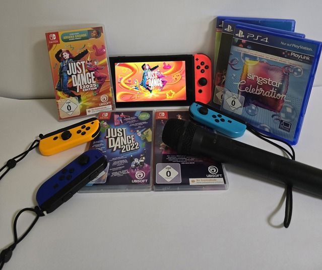 Nintendo Switch mit Just Dance Spiel, Mikrofon und PS4-Spielen auf einem Tisch.
