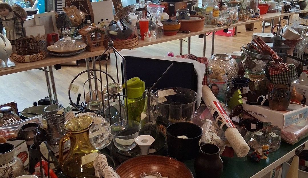 Ein Flohmarkt mit verschiedenen Haushaltsgegenständen auf Tischen ausgestellt.