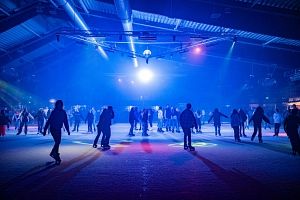 Menschen beim Eislaufen in einer beleuchteten Eishalle.