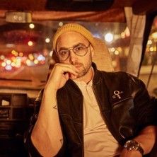 Person mit Brille und Mütze sitzt in einem Auto bei Nacht.