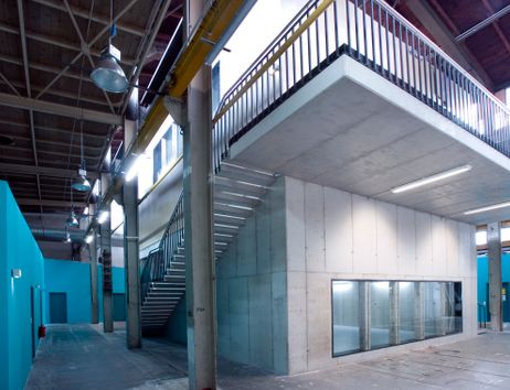 Innenansicht eines modernen Industriegebäudes mit Betonwänden, Treppe und blauen Wänden.