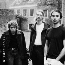 Drei Männer stehen vor einem alten Gebäude.