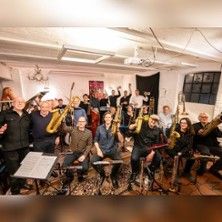 Eine Bigband mit verschiedenen Instrumenten in einem Proberaum.