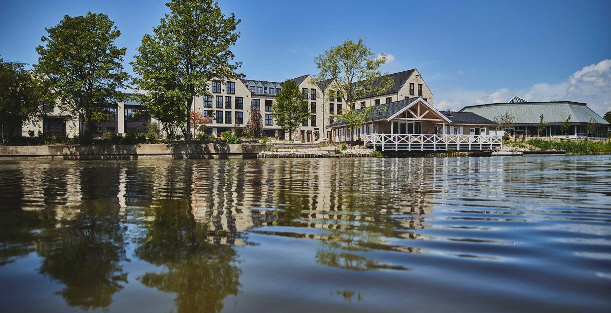 Gebäude am Flussufer mit Bäumen und klarem Himmel.