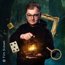 Ein Mann hält eine leuchtende Laterne, umgeben von schwebenden Objekten wie einem Bilderrahmen, einem Würfel und einer Spielkarte.