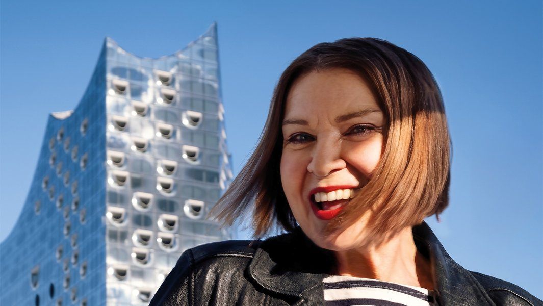 Frau vor der Elbphilharmonie in Hamburg bei sonnigem Wetter.