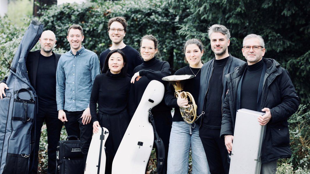 Gruppe von acht Personen mit Musikinstrumenten im Freien.