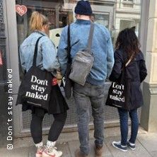 Drei Personen stehen vor einem Schaufenster in Hamburgs Schanzenviertel. Zwei von ihnen tragen Taschen mit der Aufschrift 'Don't stay naked'.