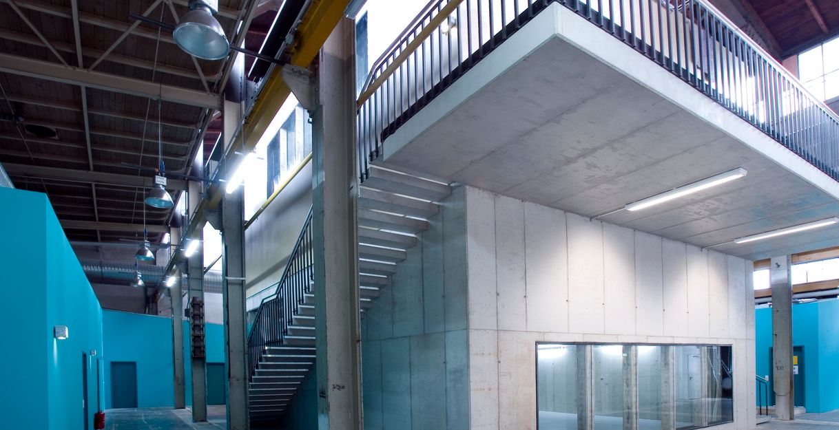 Innenansicht eines modernen Industriegebäudes mit Betonwänden, Treppe und blauen Wänden.