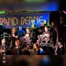 Eine Big Band spielt auf einer Bühne mit einem Banner im Hintergrund, auf dem 'Band Berne' steht.