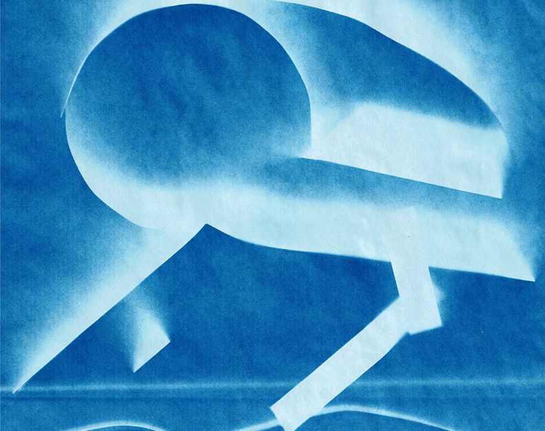 Zu sehen ist eine Cyanotypie: Vor einem blauen Hintergrund ist ein konstruiertes, abstraktes und nicht scharf abgegrenztes räumlich wirkendes Gebilde in Weiß zu sehen. Woher die bläuliche Schattenbildung kommt, lässt sich nicht recht klären.