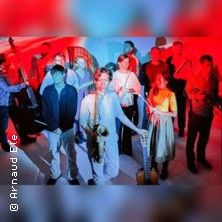 Eine Gruppe von Musikern mit Instrumenten in bunter Beleuchtung.