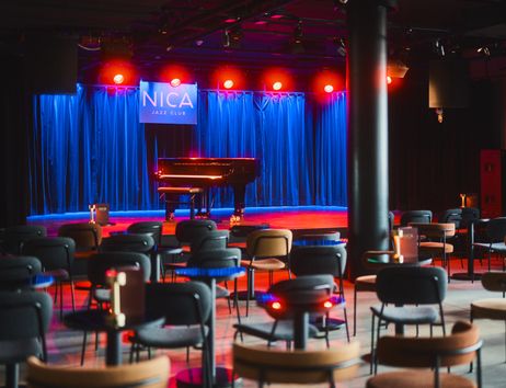 Innenansicht des NICA Jazz Clubs mit Bühne, Flügel und leeren Sitzplätzen.