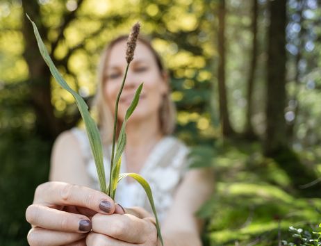 Frau entdeckt heimische Wildkräuter im Wald