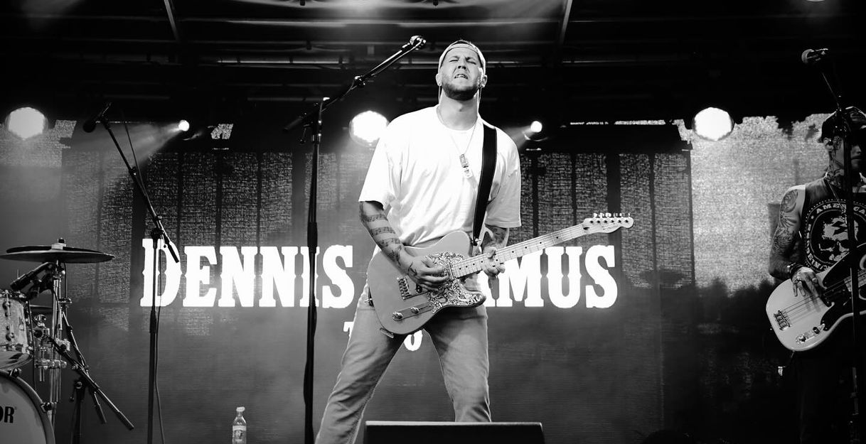 Dennis Adamus steht auf der Bühne mit geschlossen Augen und strengen Blick spielt er die E-Gitarre