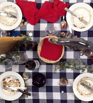 Kunstinstallation von Daniel Spoerri mit benutztem Geschirr auf kariertem Tischtuch.