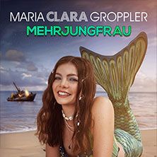 Frau mit Meerjungfrauenflosse am Strand, lächelnd, im Hintergrund ein brennendes Schiff.