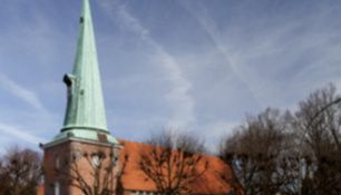 Kirche St. Johannis in Hamburg-Eppendorf mit spitzem Turm und rotem Dach.