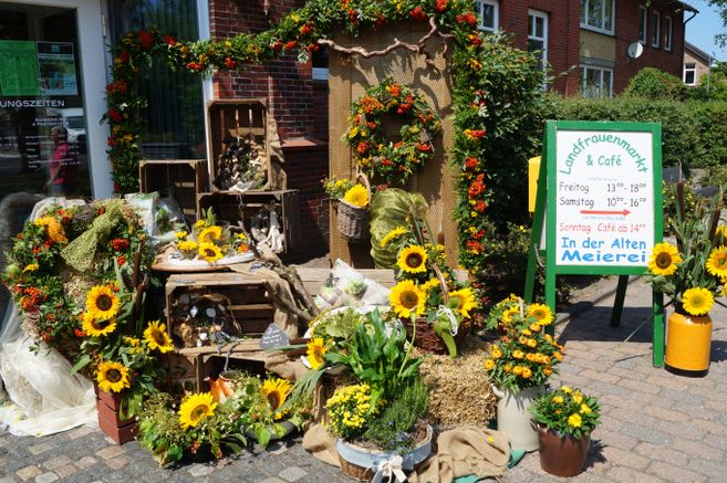 Dekorierter Eingang mit Blumen und Schild für Landfrauenmarkt.