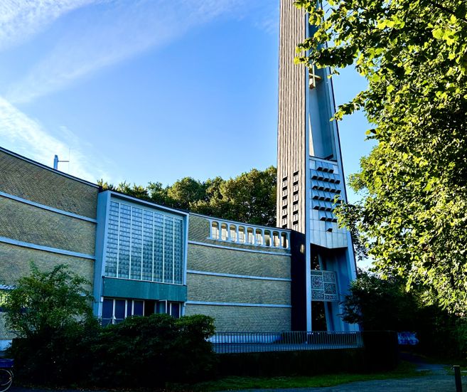 Außenansicht der Dreifaltigkeitskirche mit modernem Glockenturm und Glasfassade.