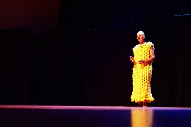 Person in gelbem Kostüm und Clownsnase auf Bühne.