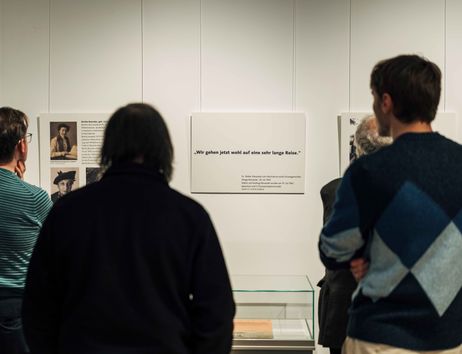 Drei Menschen stehen vor Tafeln mit Text in der Ausstellung