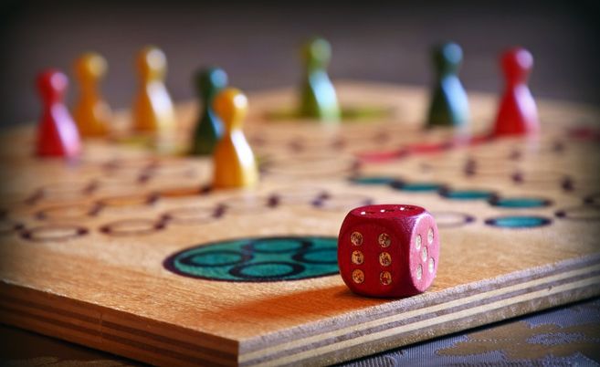 Nahaufnahme eines Brettspiels mit bunten Spielfiguren und einem roten Würfel.