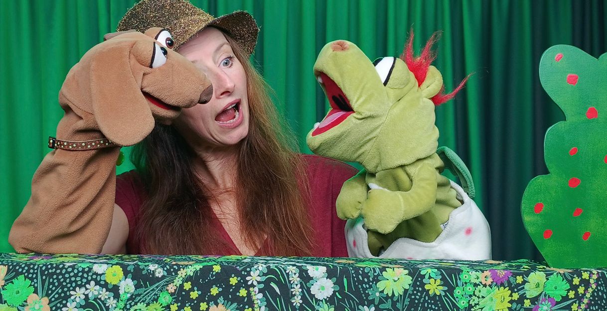 Auf dem Foto ist Puppenspielerin Maya Raue mit dem Hund Kollin Kläff und Drache Blitz im Gespräch zu sehen.